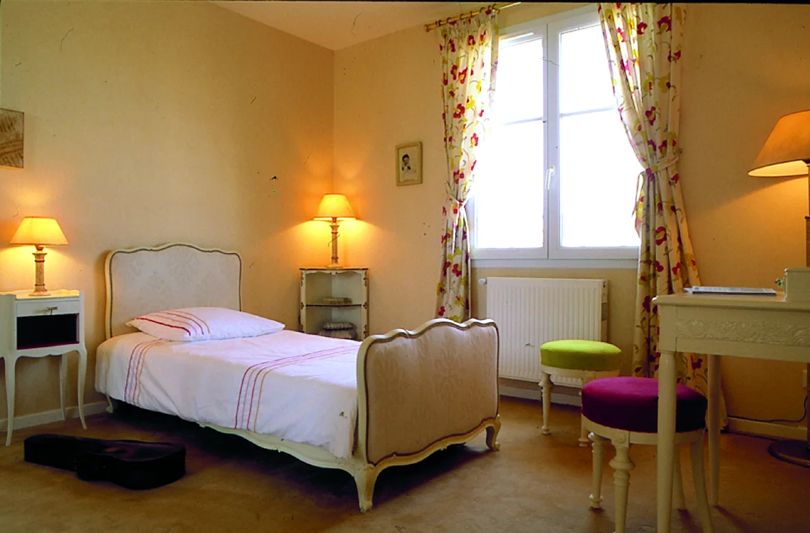 L'Aunaie, chambre de fille, lit blanc et rideaux fleuris.