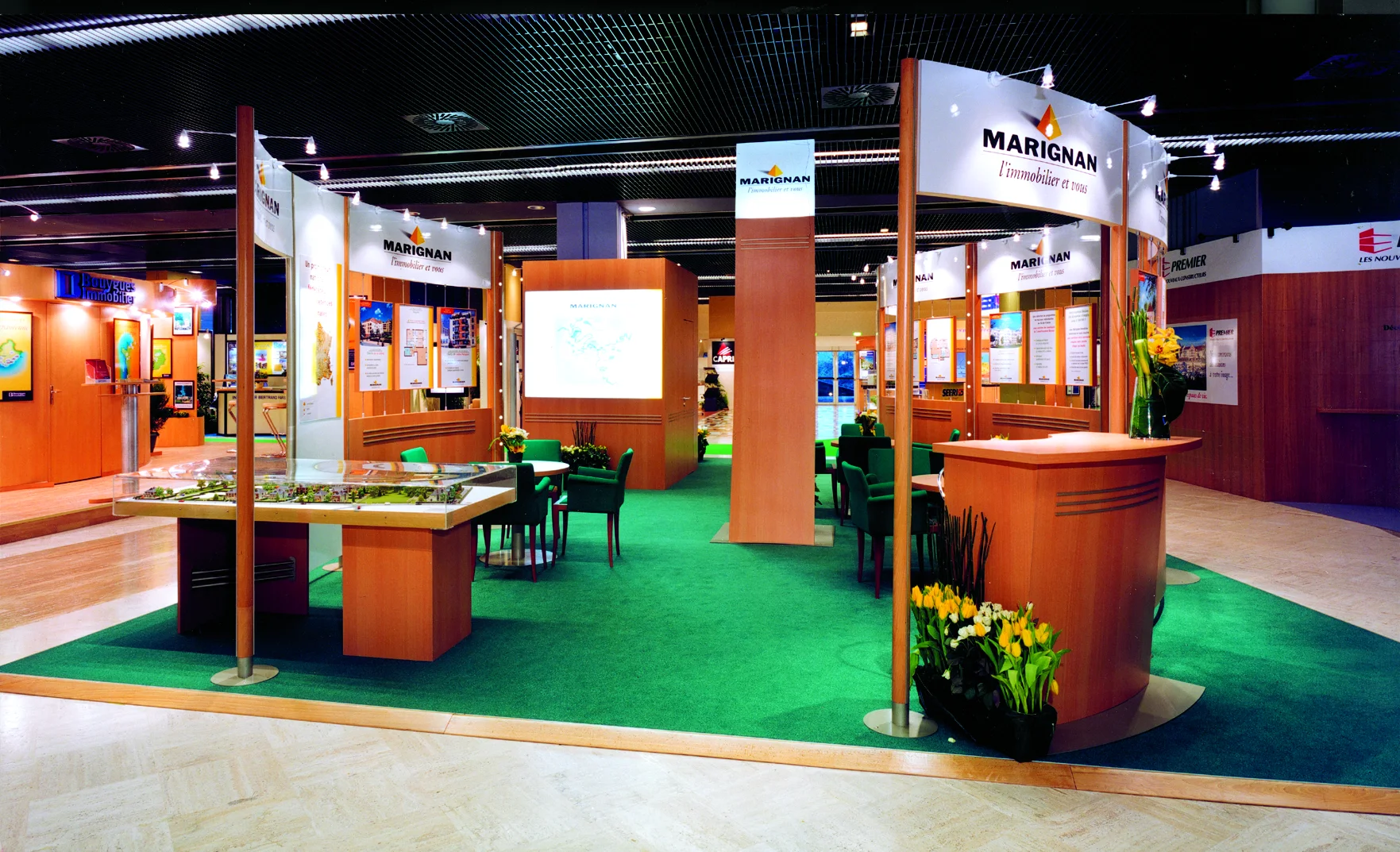 Le stand : parois de bois, moquette verte et panneaux de programmes.