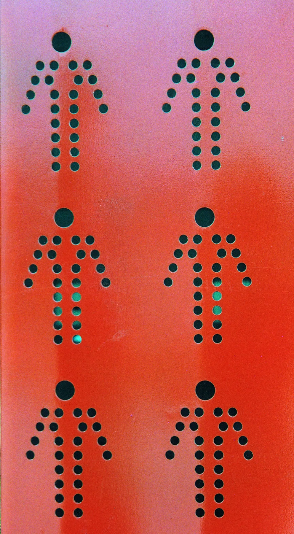 Pictogrammes d'hommes perforés dans une tôle rouge, pour les sanitaires.