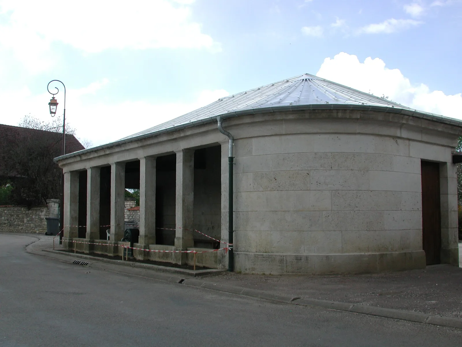 Photographie de repérage en Haute-Marne, mai 2003 : un bâtiment de pierre à colonnade au bord de la rue.