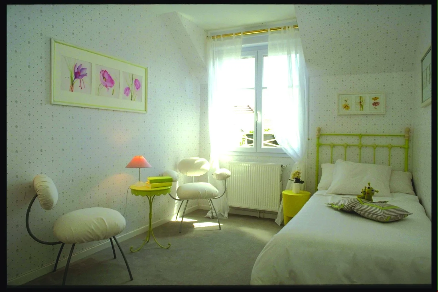 La Noiseraie, une chambre de fille au lit de laiton et aux fauteuils blancs.
