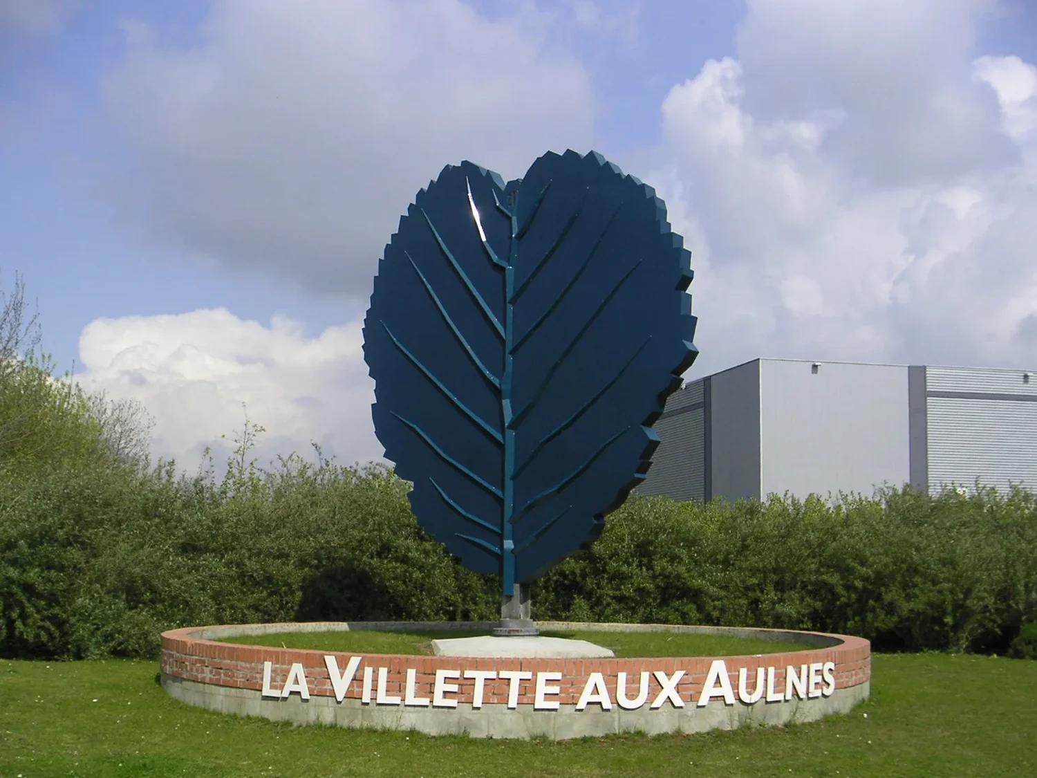 La grande feuille d'aulne bleue au-dessus de son muret circulaire « La Villette aux Aulnes ».