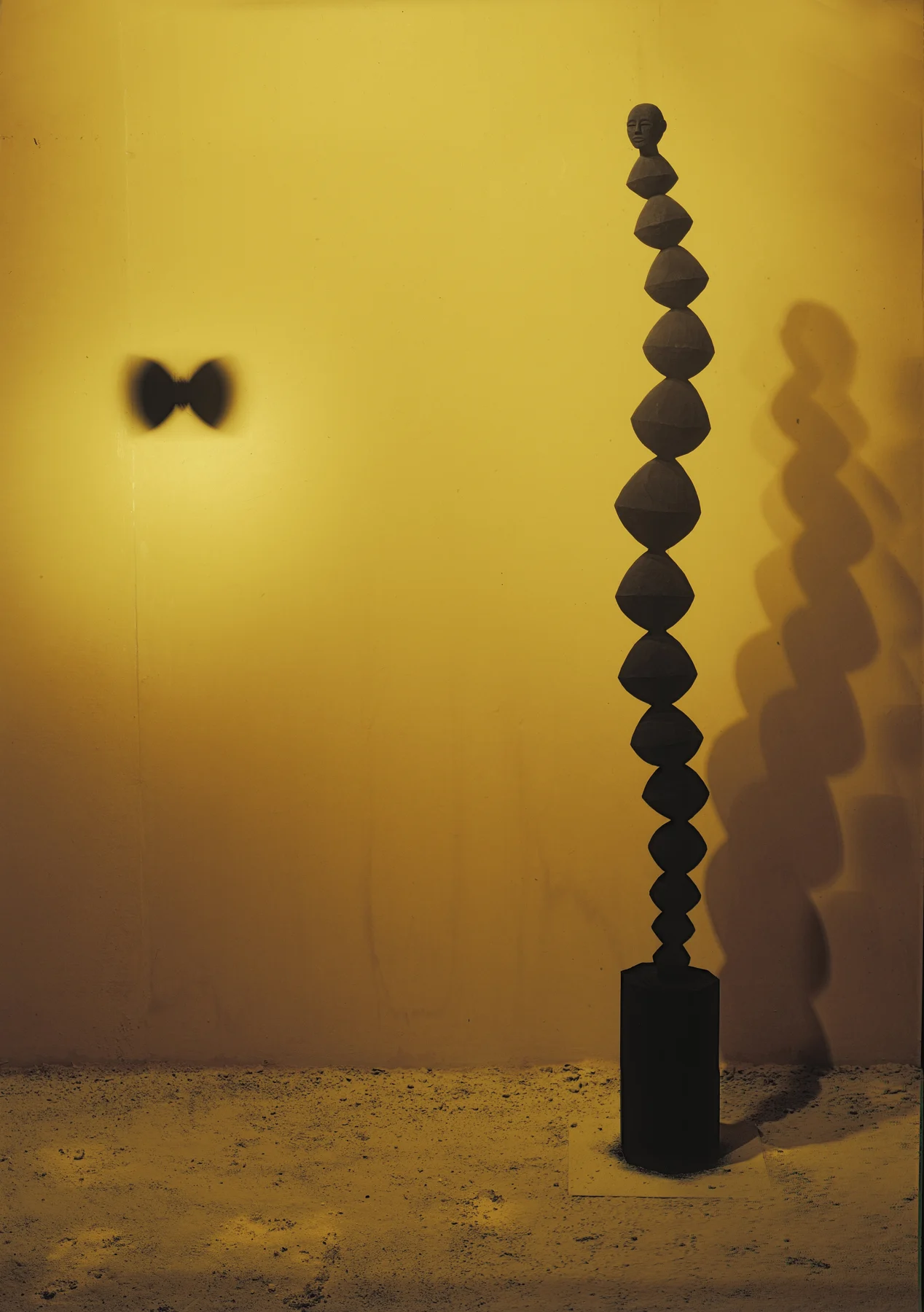 Axel Cassel, grand diabolo en bois d'iroko, colonne de diabolos surmontée d'une tête, dans une salle jaune