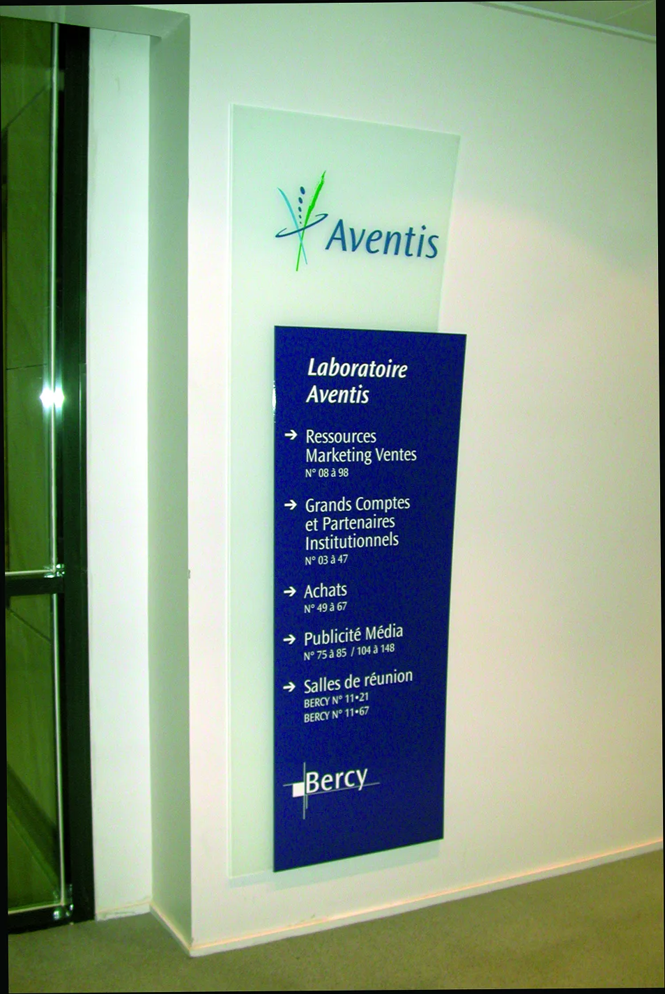 Totem d'accueil Aventis, panneau bleu nuit sur verre, liste des services de l'étage.