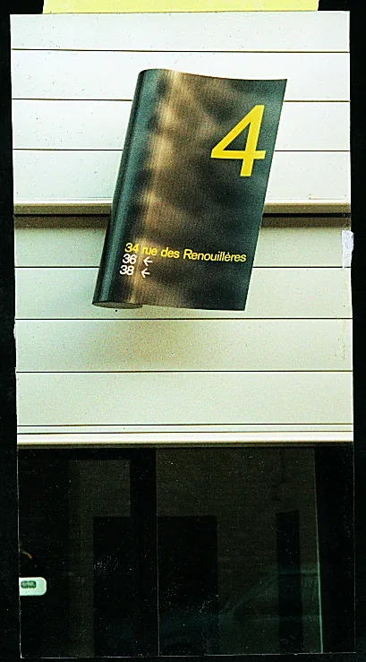 Petit panneau noir au chiffre 4 jaune fixé sur une façade.