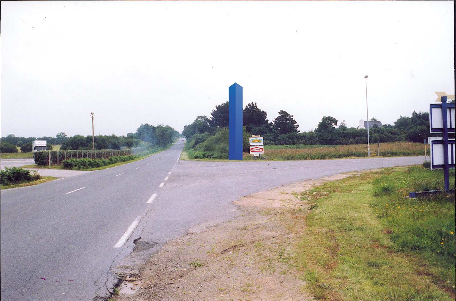 Signal bleu dressé à un carrefour de route de campagne.
