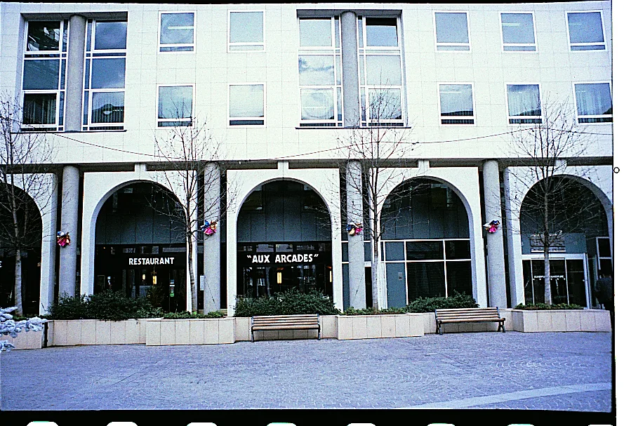 Façade d'immeuble à arcades avec la devanture d'un restaurant « Aux Arcades ».