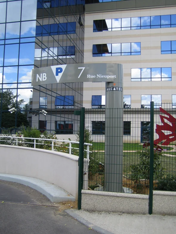 Poteau directionnel de parking : bandeau « NB, P, 7 Rue Nieuport » au-dessus d'une rampe d'accès.