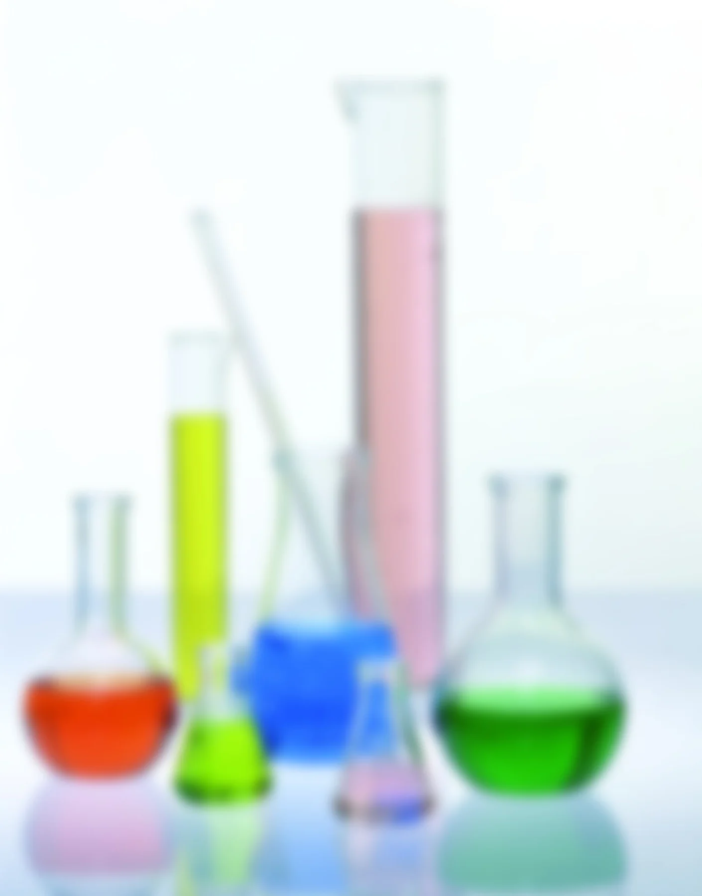 Éprouvettes et ballons de laboratoire flous, remplis de liquides rouge, jaune, bleu et vert.